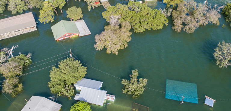 Aerial view of a severely flooded residential neighborhood with water reaching the roofs of the houses